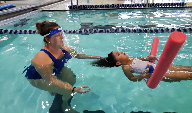 woman teaching child swimming
