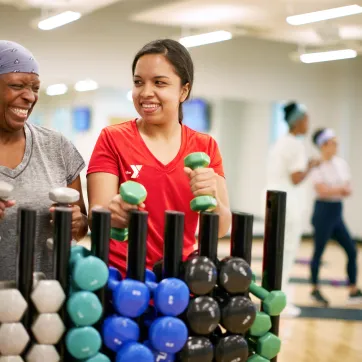 two women in a ymca fitness class pick up weights