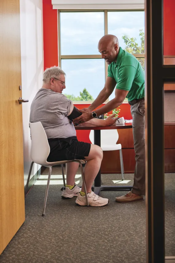 Y staff helping member do blood pressure monitoring