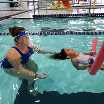 woman teaching child swimming